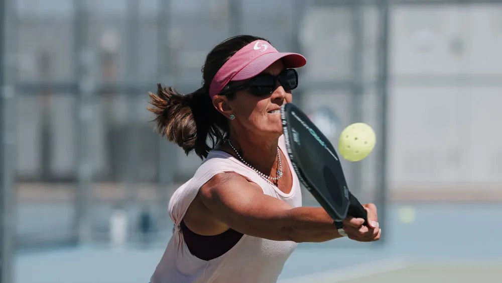Female player hitting pickleball with paddle